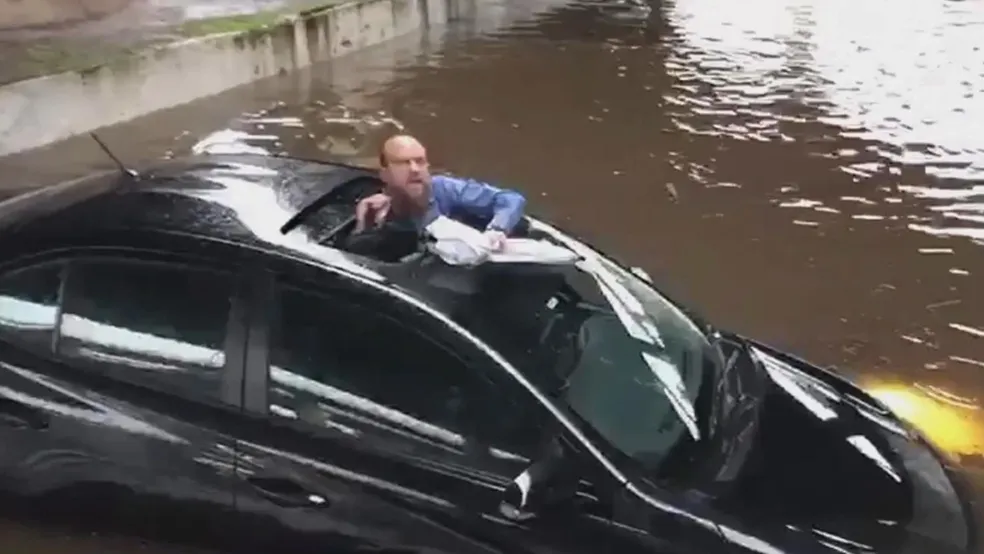 Motorista fica preso em alagamento e escapa pelo teto solar (assista ao vídeo)