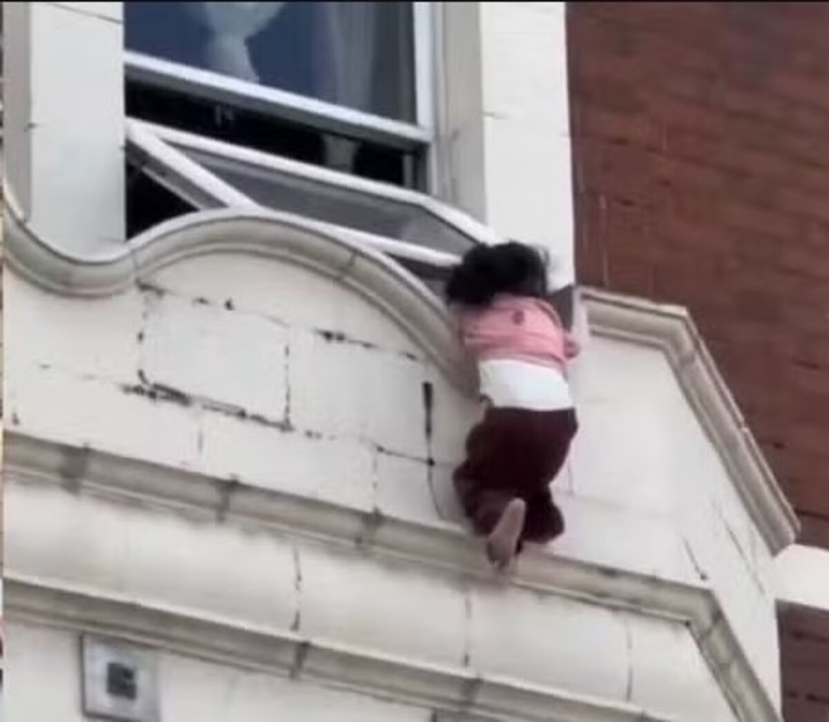 Vídeo impressionante mostra resgate de criança pendurada em janela sobre rua movimentada